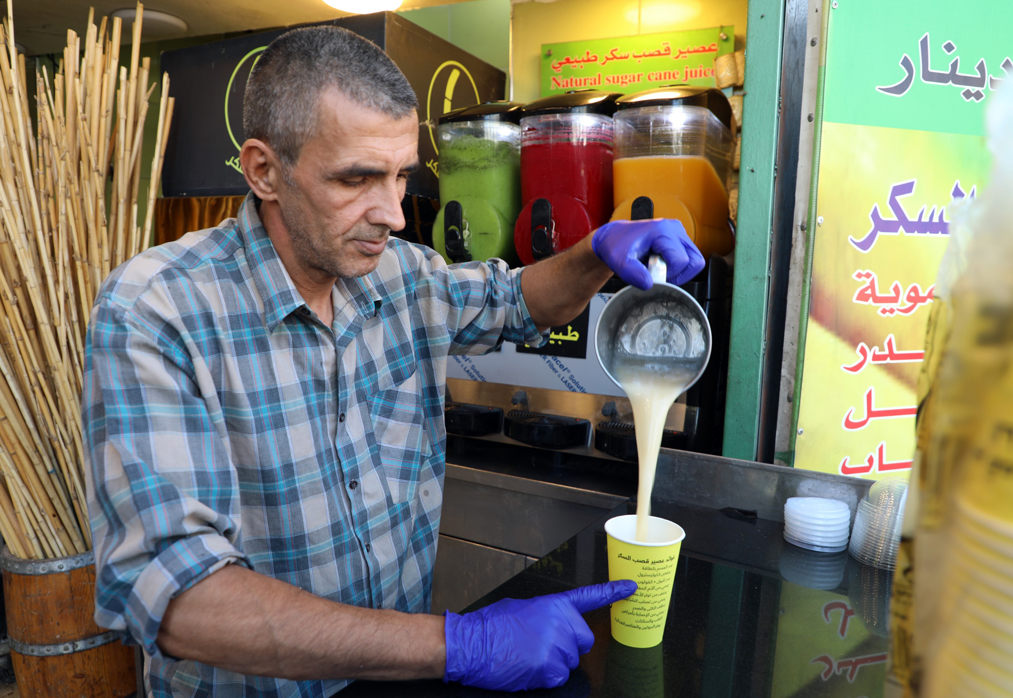 بائع في وسط البلد يقوم باعداد عصير قصب السكر الغني بفوائده الكبيرة للجسم تصوير  علي الزعبي